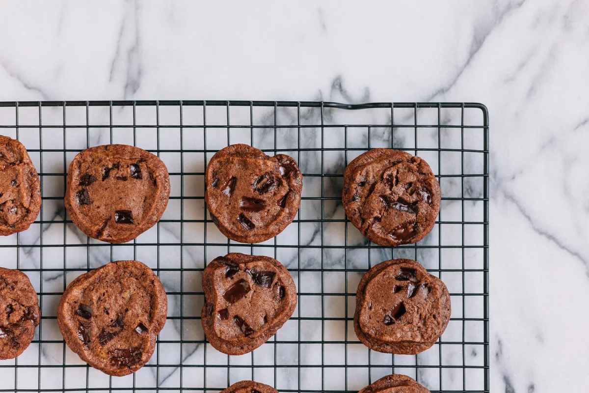 Galletas con pepitas de chocolate recién horneadas, en una rejilla sobre mármol