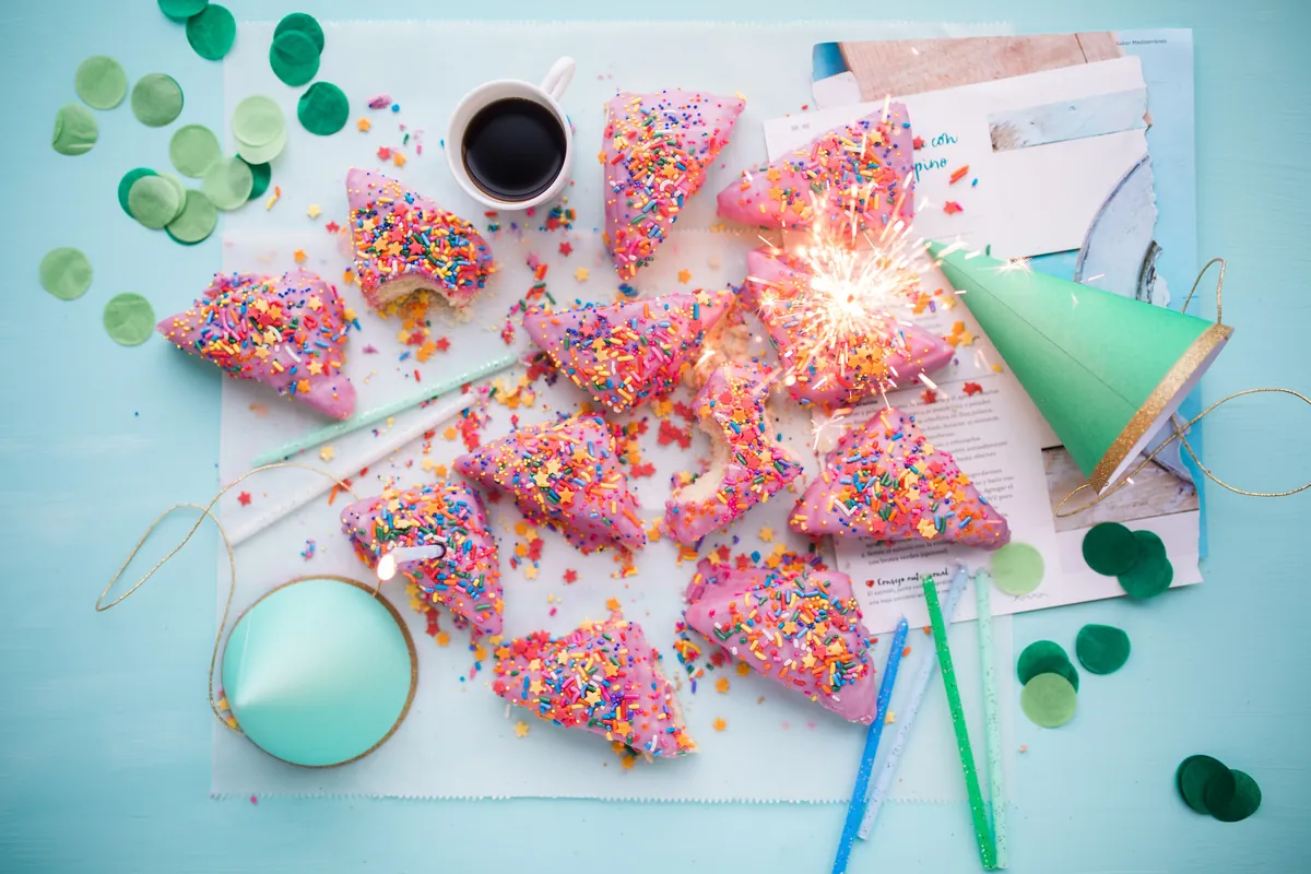 Porciones de bizcocho cubiertas de virutas de colores, con gorros de fiesta y confeti